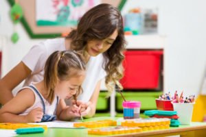 Pre-Kindergarten Girl and Teacher Painting in Classroom