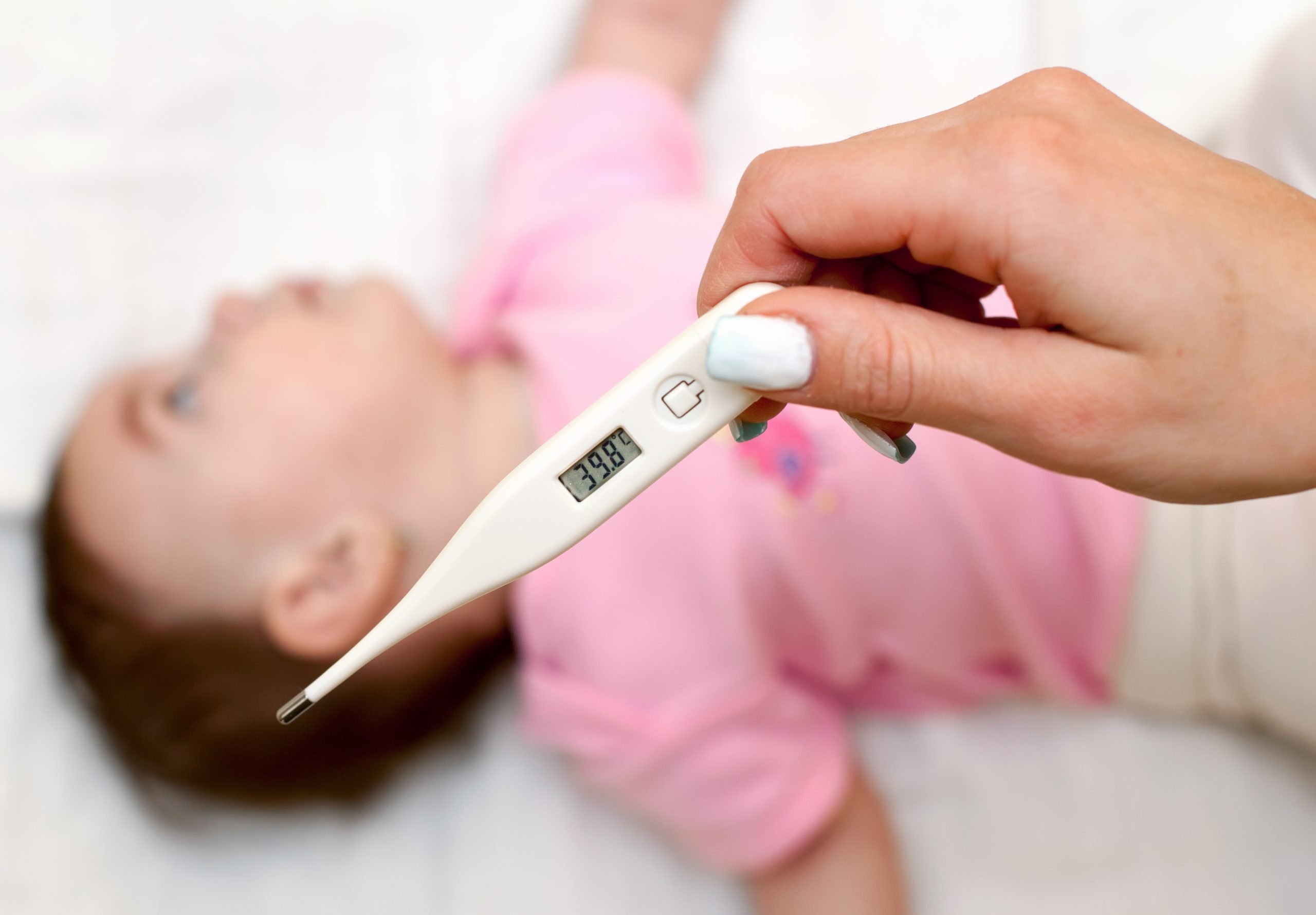 Woman in mask checking her child temperature to see if they can go to daycare